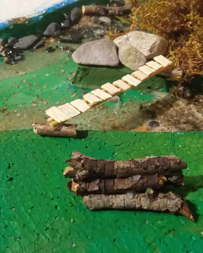 Detalle del puente de madera y pila de leña en la orilla